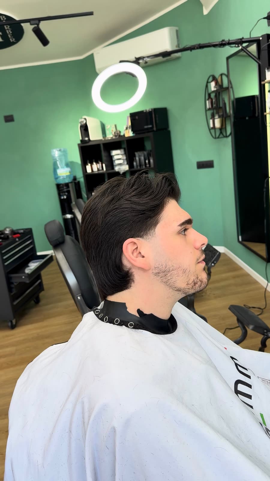 Capelli scuri con volume sopra e barba corta rifinita, visto di profilo