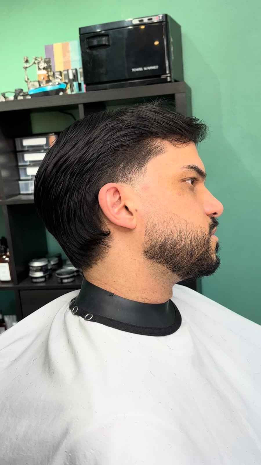 Capelli pettinati all'indietro con la nuca sfumata e barba piena rifinita, visto di profilo